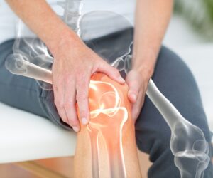 Animated knee joint overlay of man sitting and gripping knee to show joint pain.